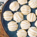 small glazed almond butter cookies on a blue plate with a tea towel