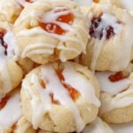 close up photo of thumbprint cookies with jam, drizzled with glaze