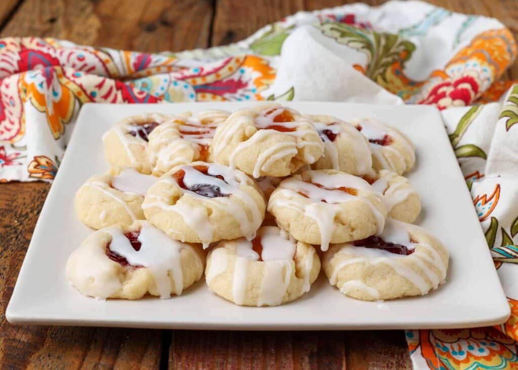 small jam thumbprint cookies stacked on square plate