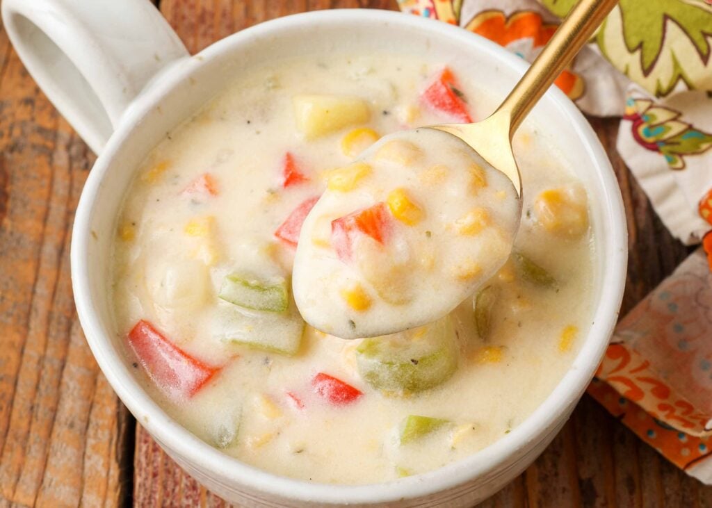 एक सफेद मग में मलाईदार सब्जी का सूप परोसने की क्षैतिज रूप से संरेखित छवि।