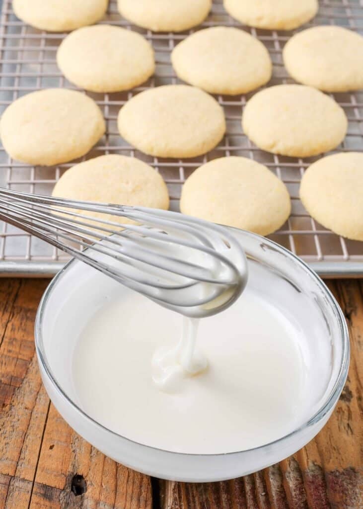Cookies on cooling rack and white icing in glass bowl