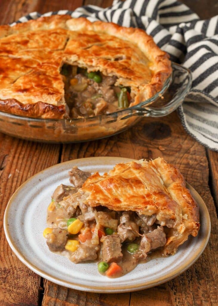 Slice of pot pie with full pie in background