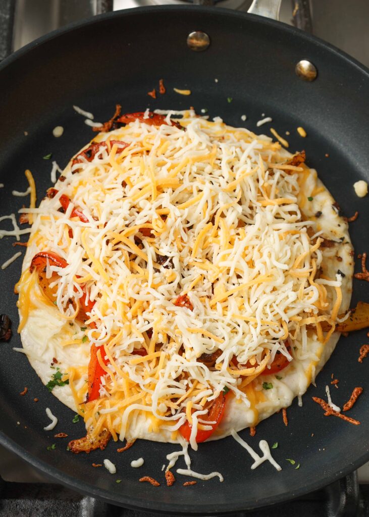 Topping the vegetables with more shredded cheese.