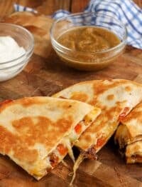 A quesadilla ready to eat with salsa visible in the background.