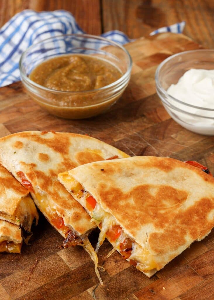 Veggie quesadilla slices are ready to eat with sour cream and salsa.