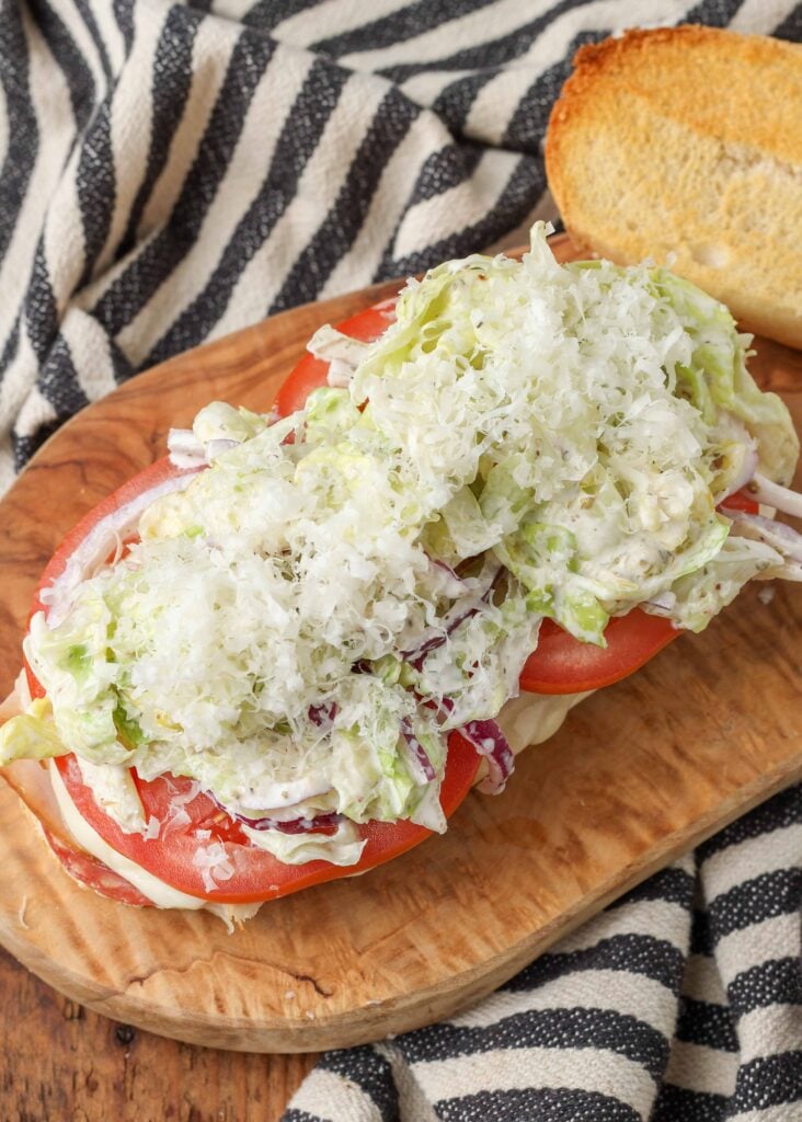 Open-top grinder sandwich with lettuce, onions, and tomato