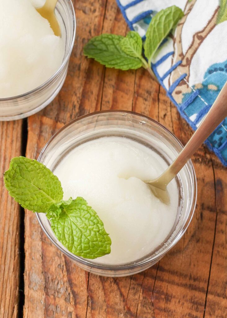 scoop of lemon sorbet in clear dish with sprig of mint