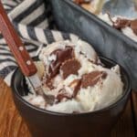 scoop of Moose Tracks Ice Cream in black bowl with spoon on wooden table