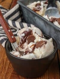 scoop of Moose Tracks Ice Cream in black bowl with spoon on wooden table