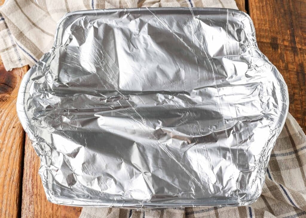 The baking dish has been covered with heavy duty aluminum foil in this top down image.