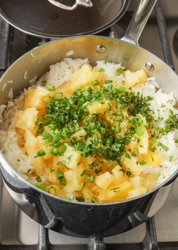 adding pineapple and cilantro to pot of rice