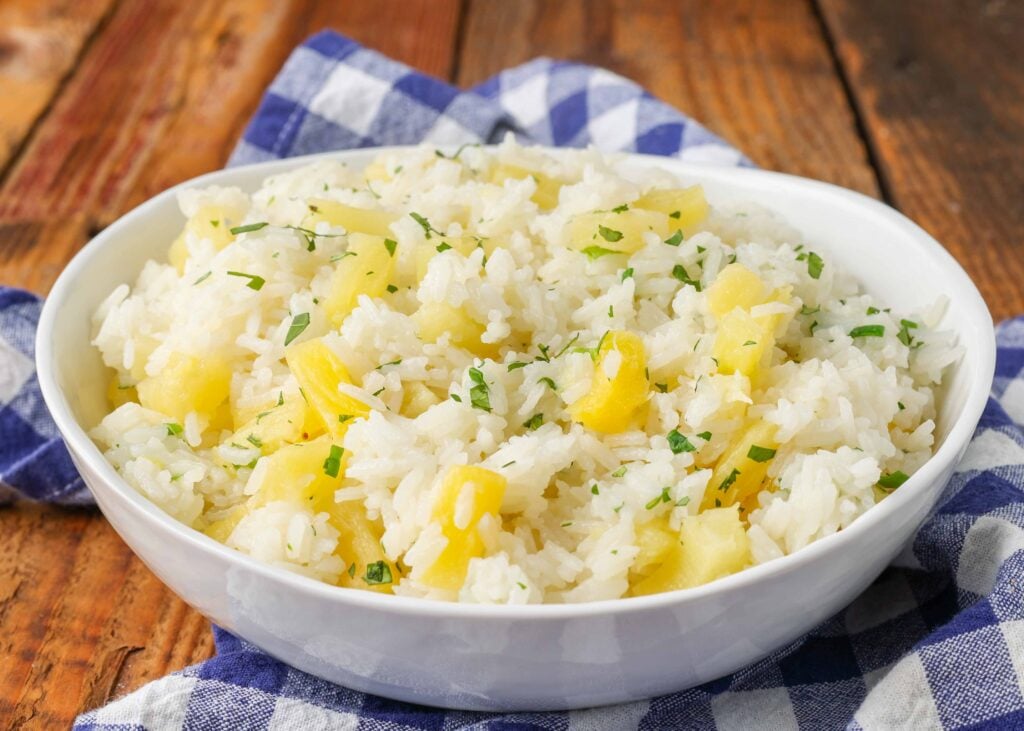 pineapple and rice in white bowl over blue napkin