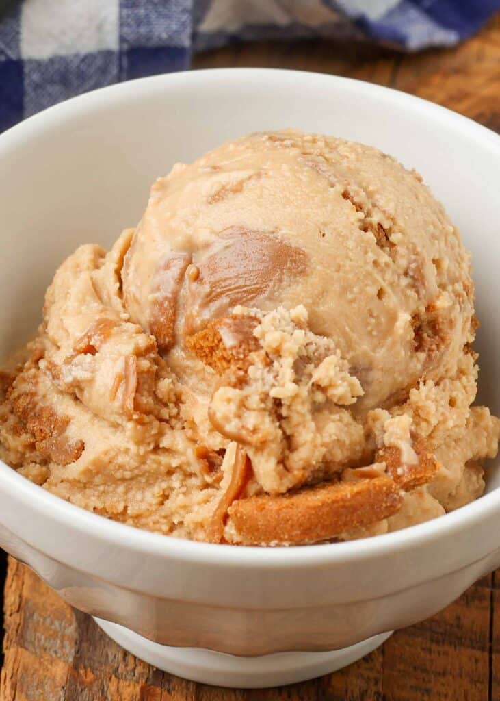 scoop of cookie butter ice cream in small white bowl next to blue napkin