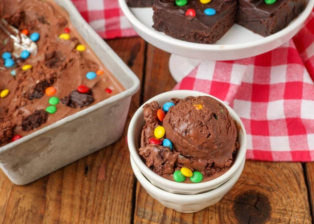 scoop of chocolate ice cream with brownies and candies in small white bowl