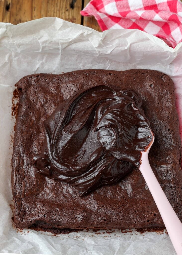 spreading cooled frosting over brownies