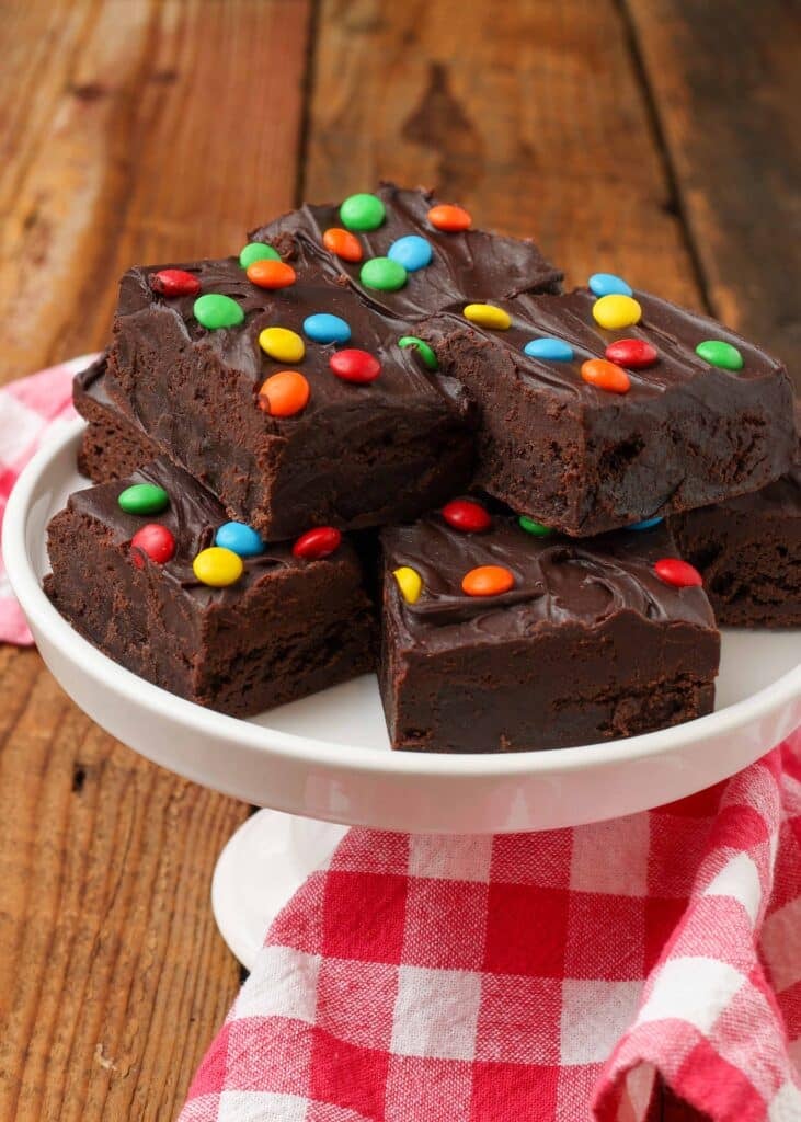 stacked fudgy brownies on plate with a checkered napkin