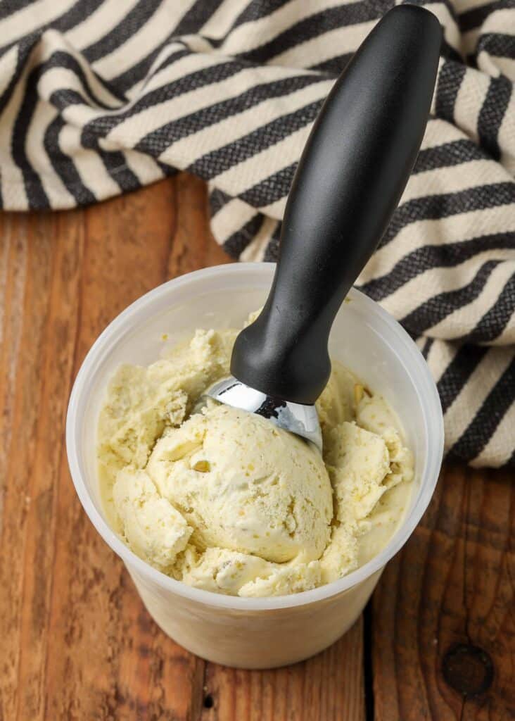 ice cream scoop in container of ice cream on wooden table