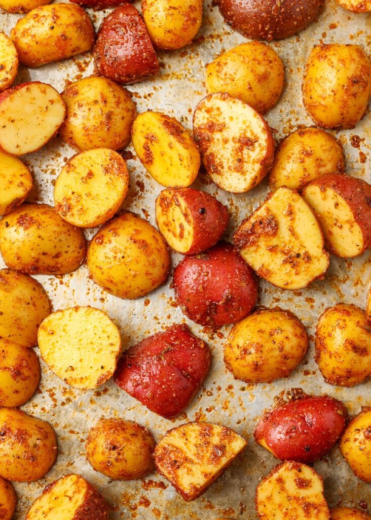 potatoes with oil and spices on baking sheet