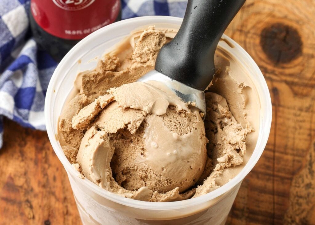 close up of ice cream scoop in container of ice cream next to dr pepper bottle