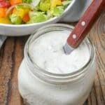 green chile ranch dressing in jar with spoon next to salad bowl