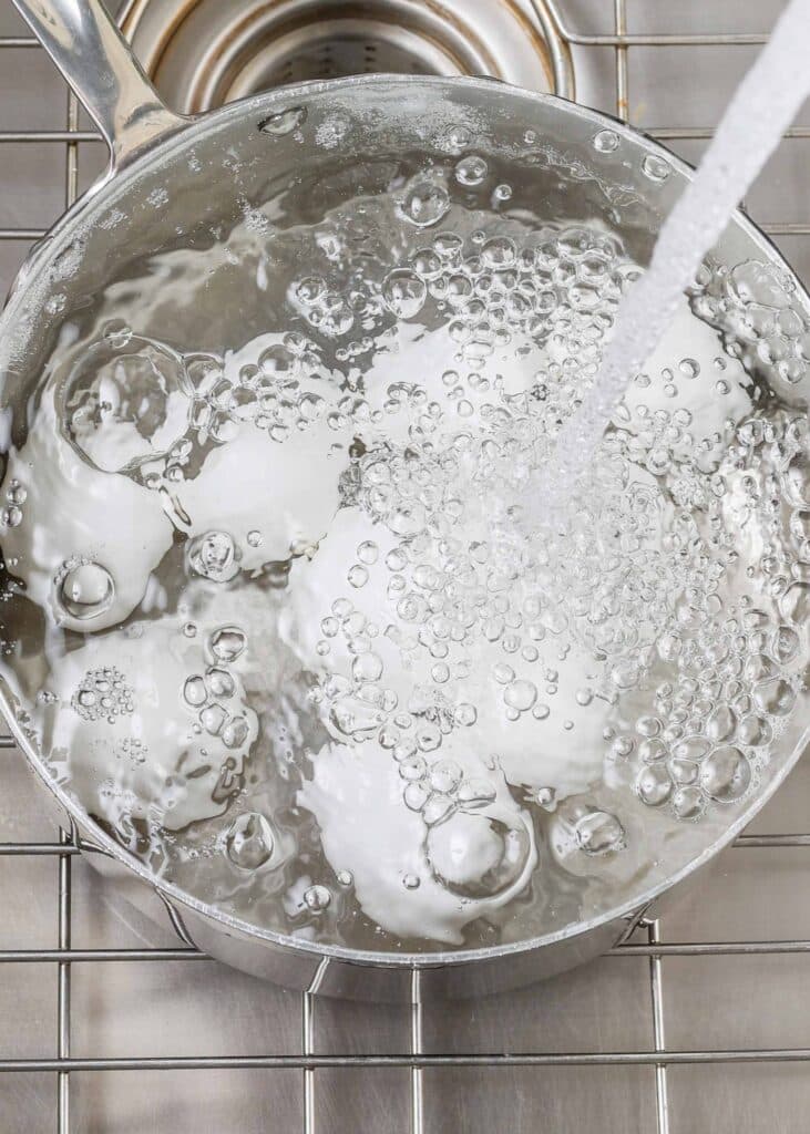 Adding cold water to pot of boiling water with eggs
