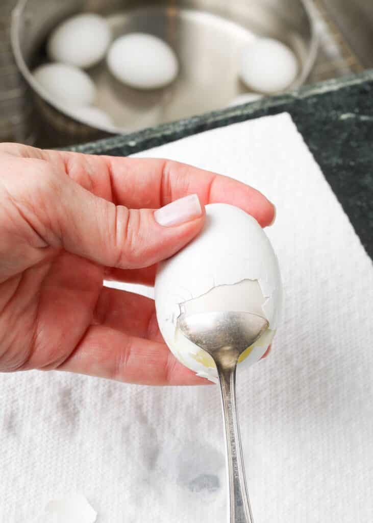 Peeling hard boiled egg with spoon
