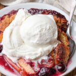 Peach blueberry cobbler in a bowl with a scoop of vanilla ice cream
