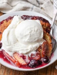 Peach blueberry cobbler in a bowl with a scoop of vanilla ice cream