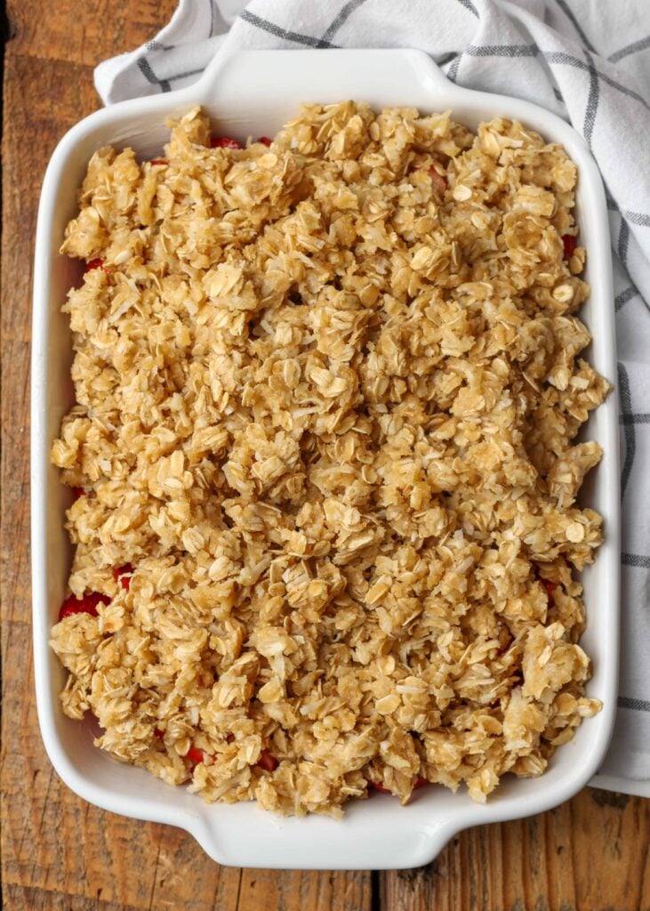 Unbaked oat topped strawberry crisp in a white ceramic pan.