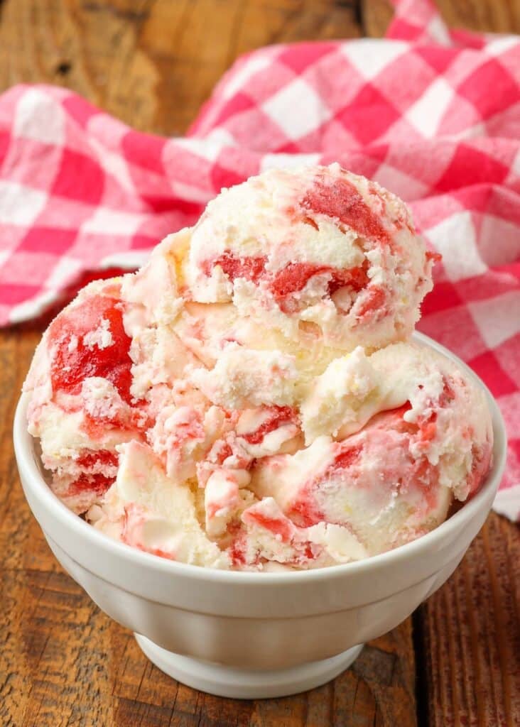 Strawberry lemonade ice cream scooped into a bowl with a red and white tea towel