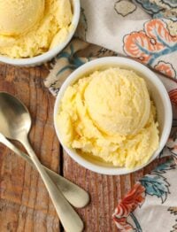 overhead shot of mango ice cream on wooden table with gold spoons