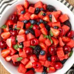 fruit salad with watermelon, cherries, blueberries, blackberries, mint, and a honey lime dressing
