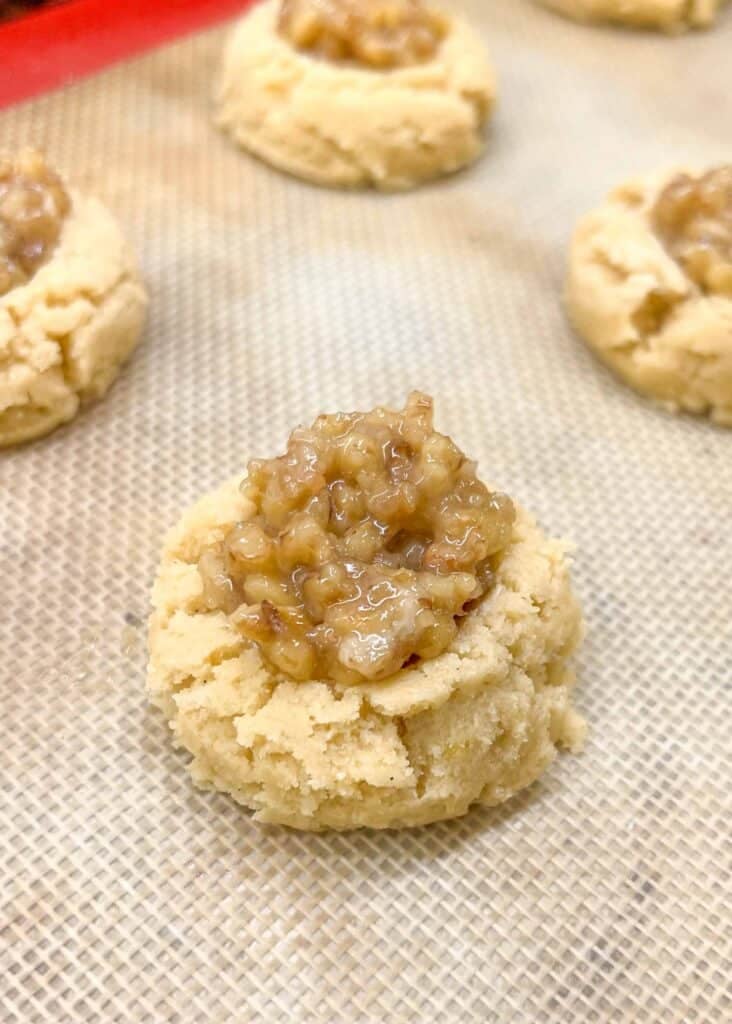 thumbprint cookie with walnut filling on baking sheet