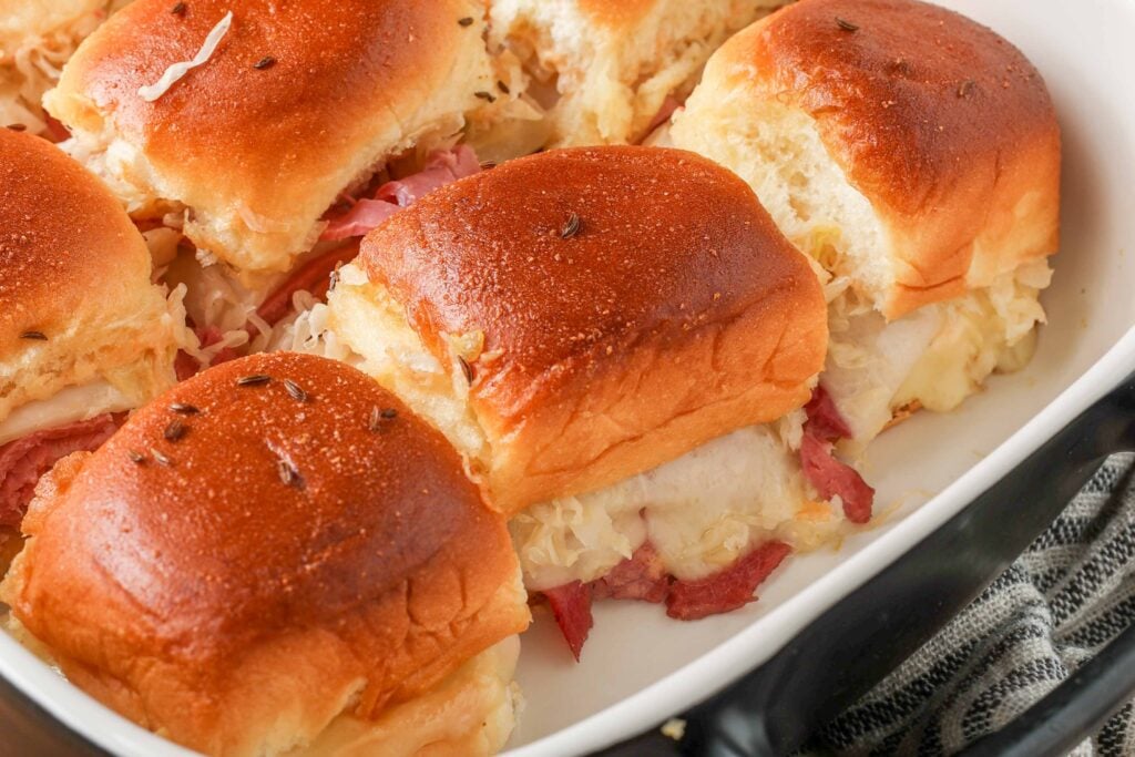 close up of sliders with melting cheese in baking dish