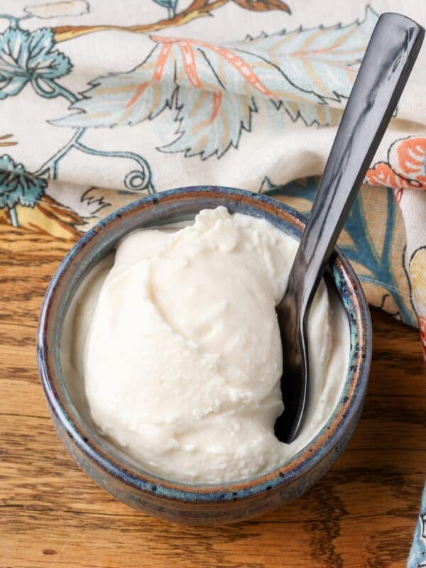 A vertically aligned image of a scoop of horchata ice cream in a small bowl on a wooden tabletop