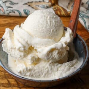 A giant scoop of luscious sea salt ice cream in a blue ceramic bowl on a wooden tabletop.