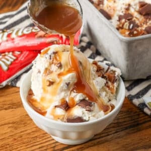 A vertically aligned image of an action shot, drizzling caramel sauce over a small bowl of ice cream.