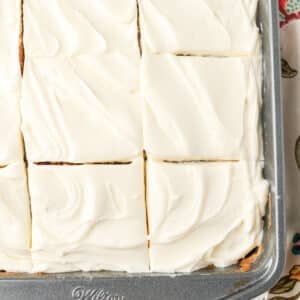 A top down photo of the frosted cake in the metal pan, sliced into squares.