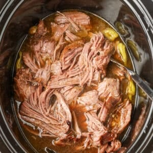 The roast has been pulled apart and returned to the crockpot in this top down photo. The meat is resting in it's juices, almost ready to serve.