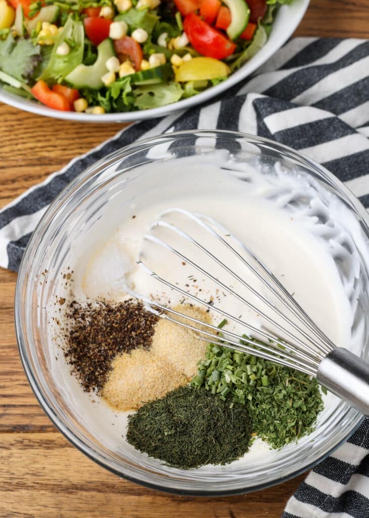 spices with mayo and sour cream in mixing bowl with whisk next to salad - 6