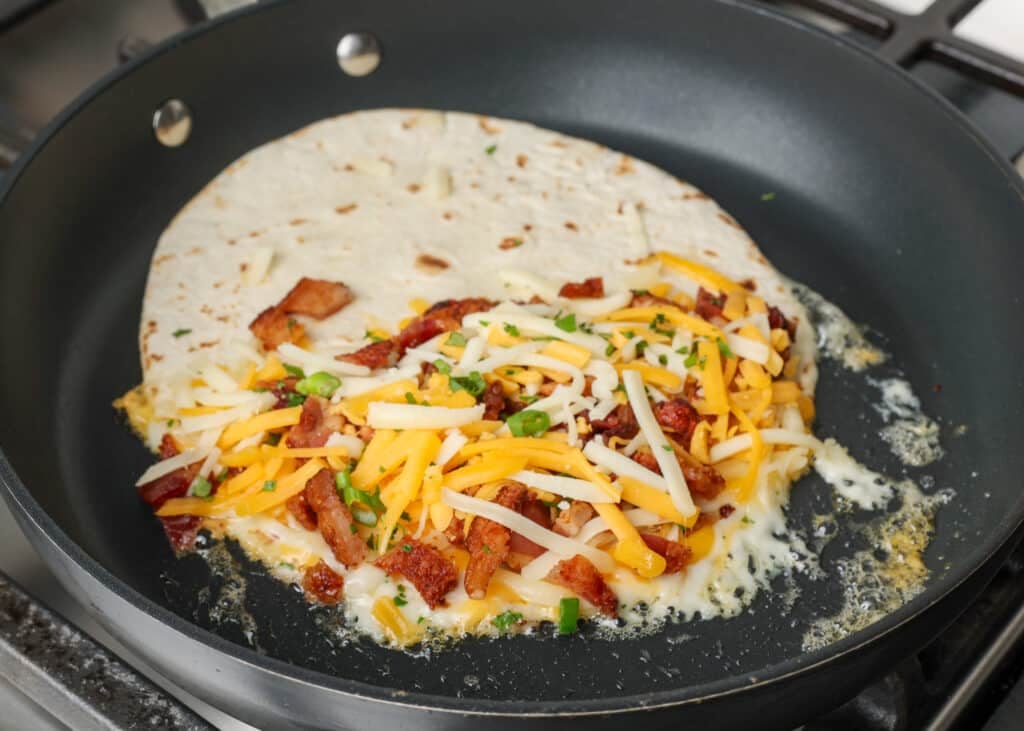 The final layer of cheese and the green onions have been sprinkled over the bacon.
