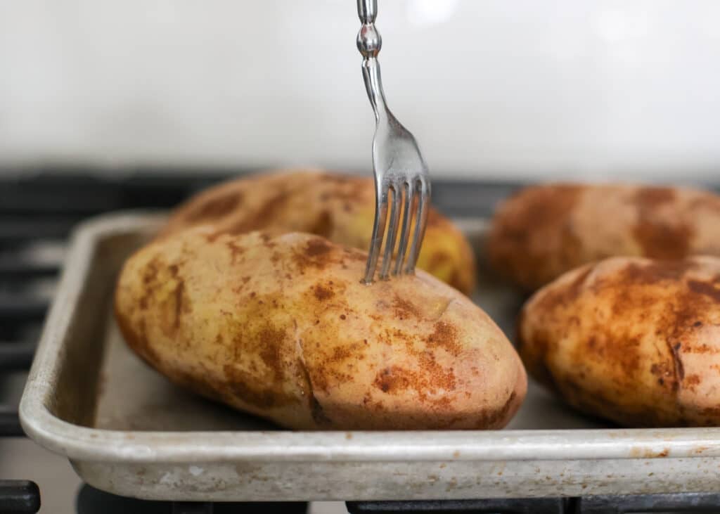 Piercing the potatoes with a metal fork.