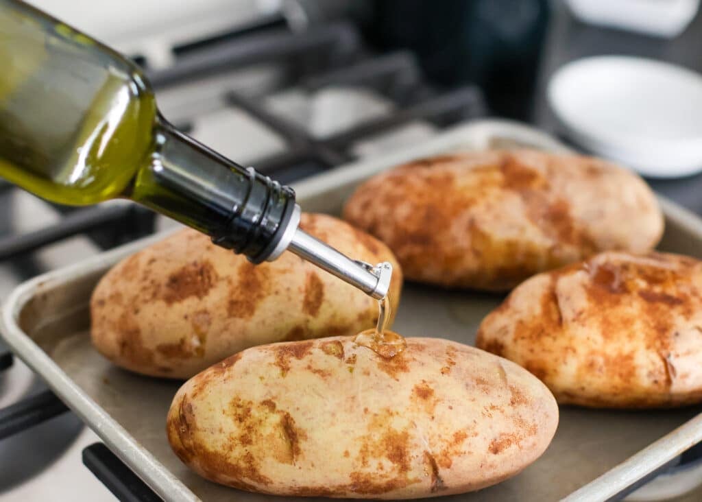 Drizzling olive oil over the potatoes on a sheet pan.
