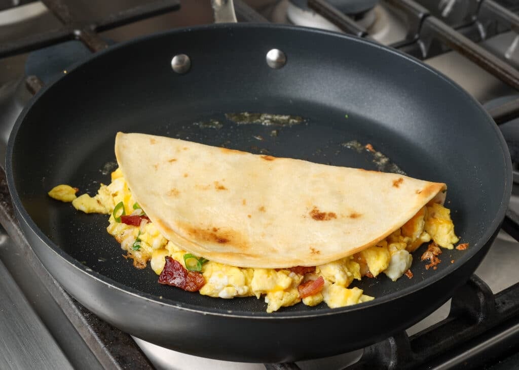 The Folded breakfast quesadilla sits in a non-stick pan, ready to flip.