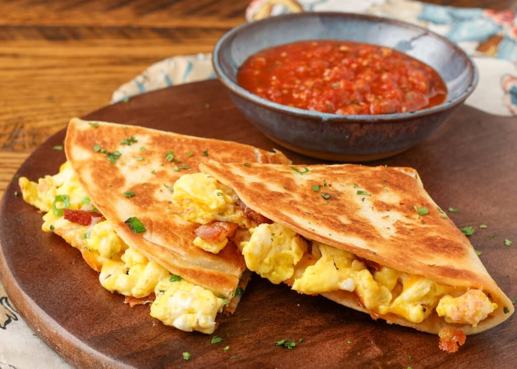A close up of the eggs, bacon, and gooey cheese seen from the edge of the breakfast quesadilla.