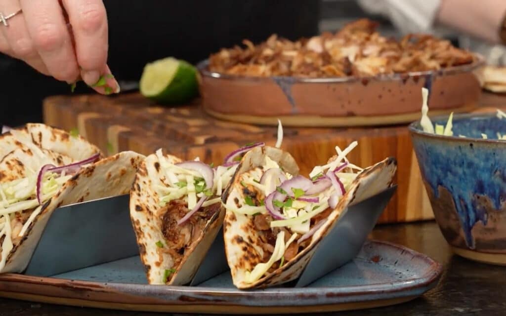 topping each taco with a sprinkle of cilantro