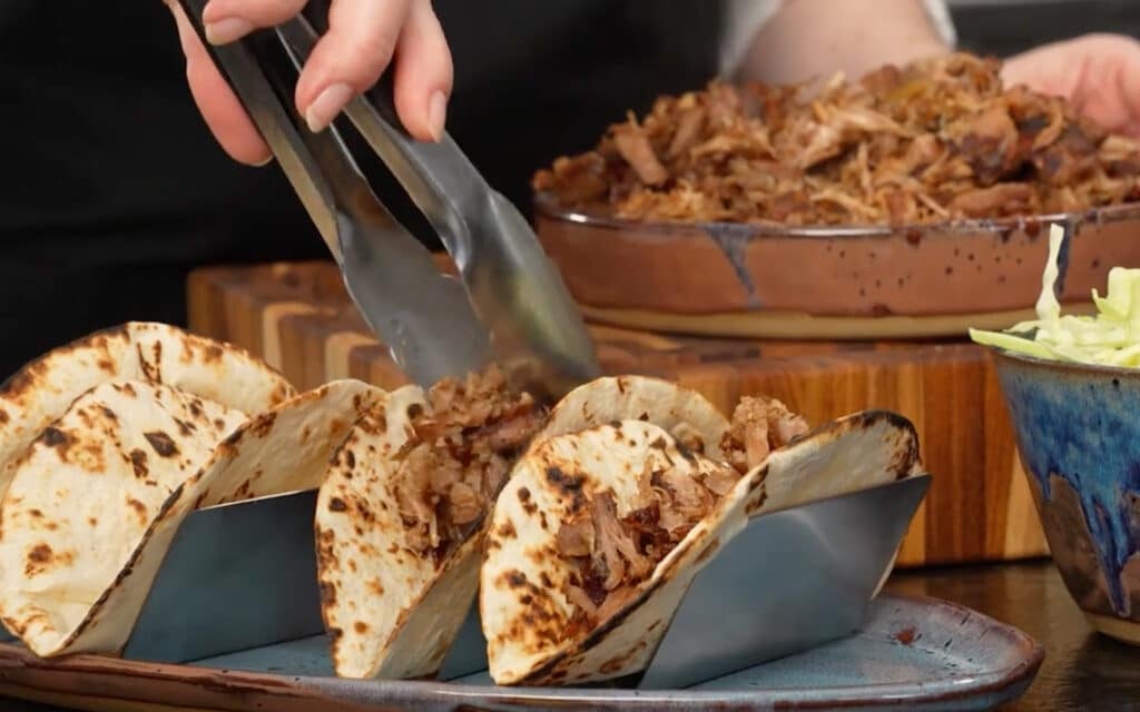 layering the meat into hot tortillas