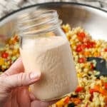 A horizontally aligned image of a jar of chipotle ranch held over the ingredients for this incredible salad.