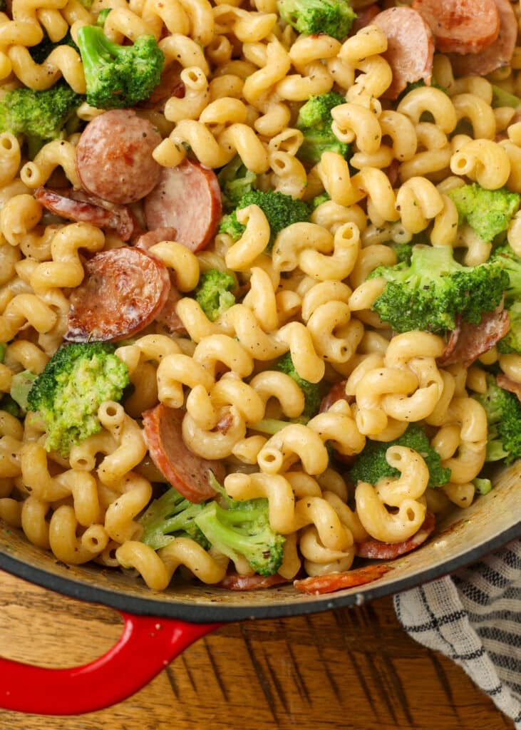 creamy kielbasa pasta with broccoli in red enamel pot on table