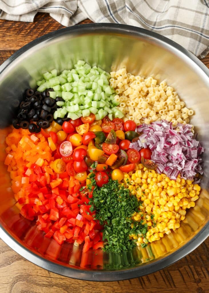 All the ingredients are arrayed in a metal mixing bowl for the pasta salad.